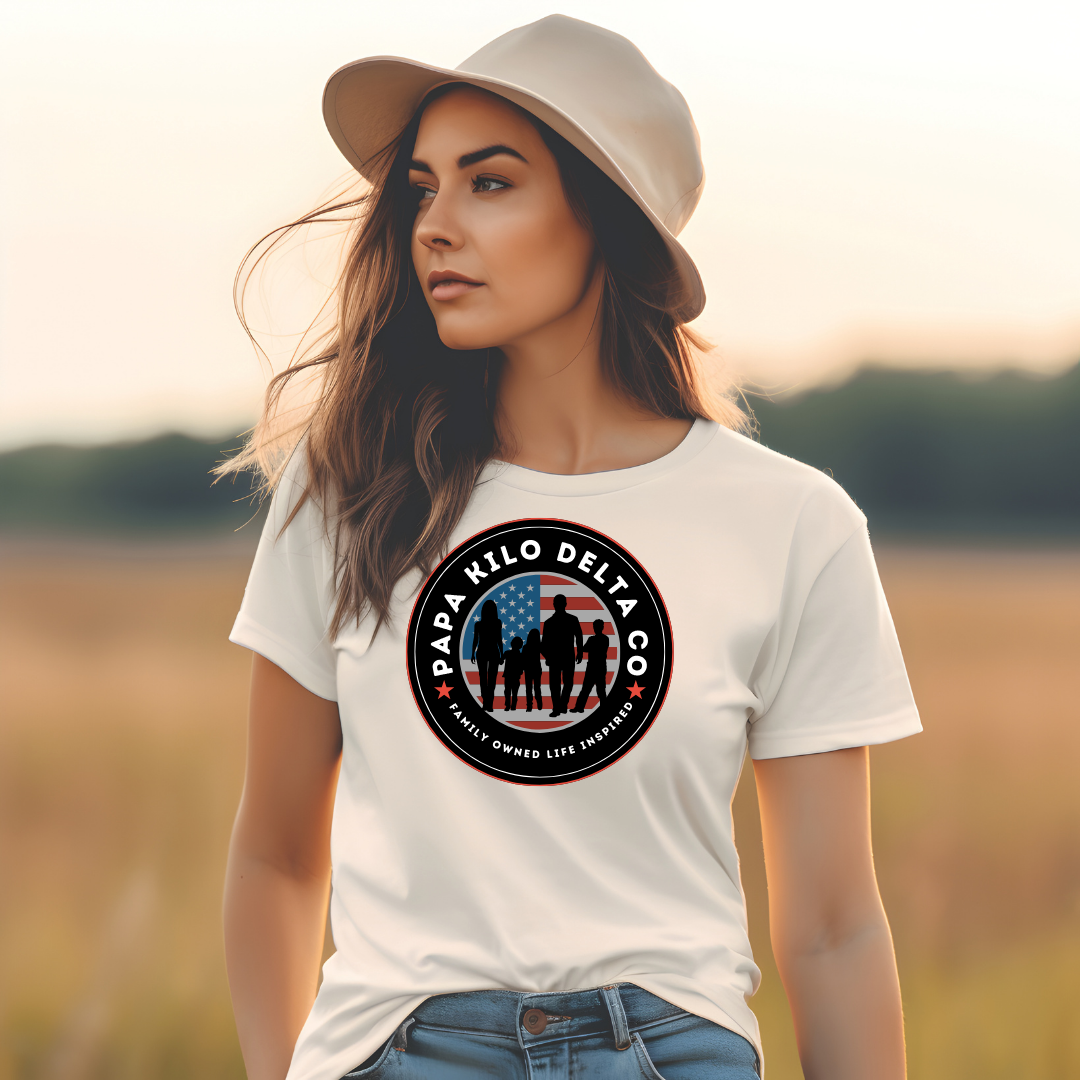 a woman standing in a field with a papa kilo delta brand graphic t-shirt on